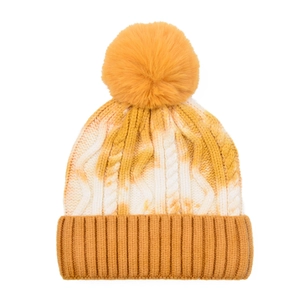 Detailed knit texture of tie-dye beanie with large mustard yellow faux fur pom-pom