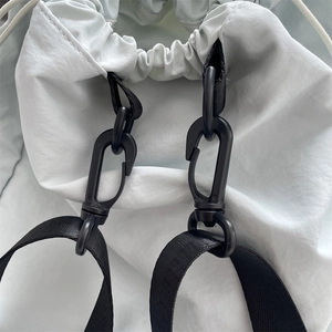 Close-up of durable black plastic snap hook and high-density nylon strap on grey drawstring bag