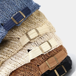 Close-up of adjustable metal buckle and woven texture on straw newsboy caps in various colors