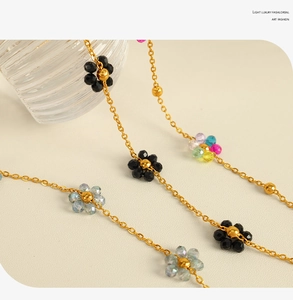 Detailed macro view of colorful crystal flower charms on a delicate gold chain necklace