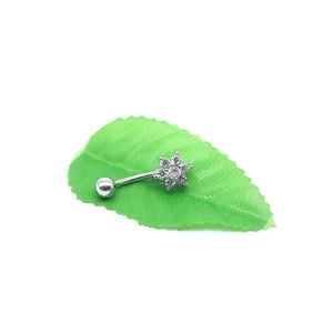 Vue détaillée du piercing de nombril fleur argentée avec cristaux sur feuille verte