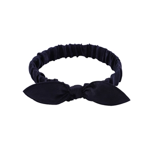 Detail of navy blue satin bow headband featuring flexible elastic gathered design