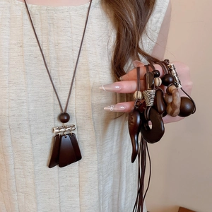 Detail of vintage wooden pendant necklace with geometric tassels on linen background