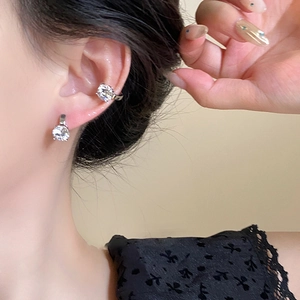 Dettaglio di un set di ear cuff in argento con zirconi scintillanti indossati sul modello