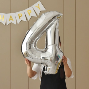 Silver 40-inch number 4 foil balloon held against a wall with Happy Birthday banner