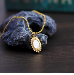 Macro shot of oval gold pendant with white mother-of-pearl shell and sunburst texture