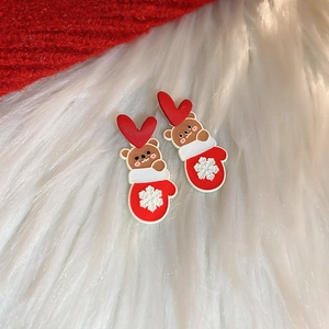 Close-up of festive Christmas bear earrings with red snowflakes on soft white faux fur