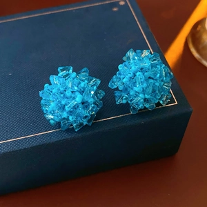 Close-up of bright blue beaded flower cluster earrings on a luxury jewelry gift box