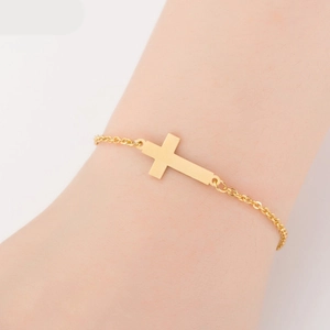 Close-up of a minimalist golden cross bracelet on a female wrist with delicate chain link