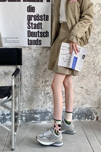 Detail of cute cartoon mid-calf socks paired with a khaki skirt and casual sneakers