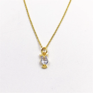 Detailed close-up of golden owl pendant featuring a clear zircon body and purple eyes