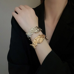 Detailed close-up of gold and silver irregular textured lava bracelets on a model