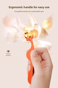 Close-up of orange eyelash applicator with ergonomic handle and curved clamp for lashes