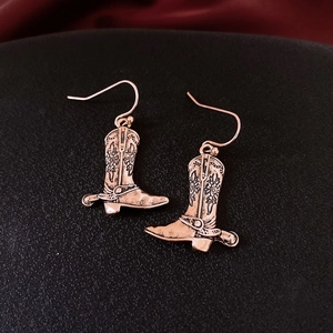 Detailed macro view of vintage cowboy boot earrings with floral engraving and spur detail