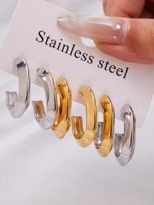 Three pairs of polished stainless steel oval hoop earrings in gold and silver finishes