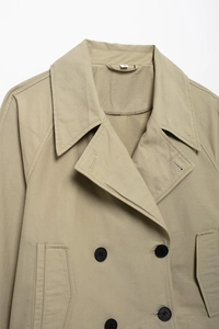 Detail of khaki cropped trench jacket featuring lapel collar, buttons and twill texture