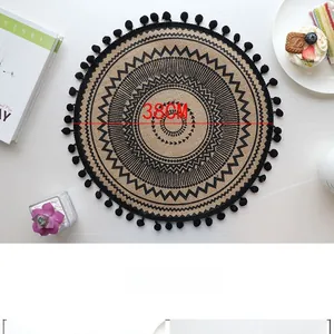 Detail view of 38cm handmade jute placemat with black geometric patterns and pom-poms