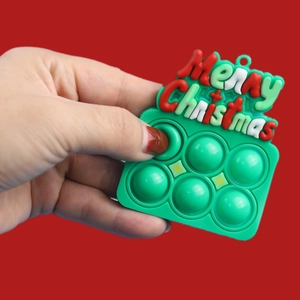 Green Christmas push pop silicone keychain toy featuring Merry Christmas text on red background