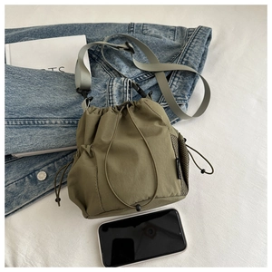 Detail der grünen Nylon-Beuteltasche mit Netzseitentasche und grauem Schultergurt