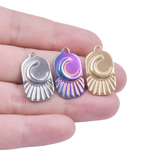 Stainless steel moon pendant in gold, silver and rainbow colors held for size scale