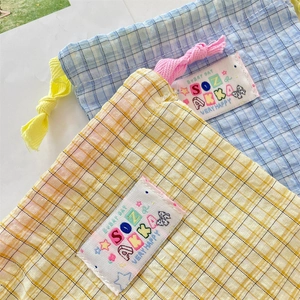 Detail of yellow and blue plaid drawstring bags with colorful text label for storage