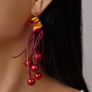 Close-up of vibrant red and yellow beaded tassel earrings worn by a female model