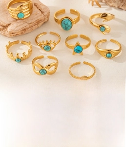 Detailed set of nine gold titanium steel rings with turquoise stones on stone props