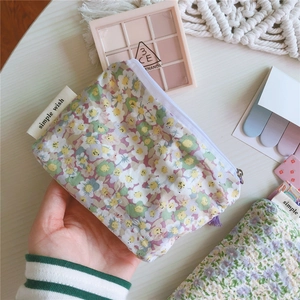Gros plan d'une pochette fleurie en coton avec fermeture éclair et étiquette tissée