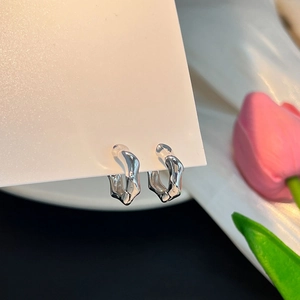 Détail macro de boucles d'oreilles géométriques argentées au fini métallique poli sur carte