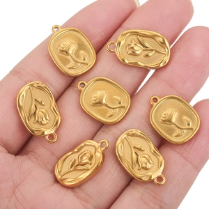 Handheld view of seven 18K gold plated stainless steel rose flower oval pendants