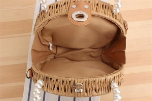 Détail du sac rond en paille avec anse en perles, doublure en tissu et fermoir métal