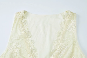 Detail shot of the V-neck lace trim and floral embroidery on this beige summer dress