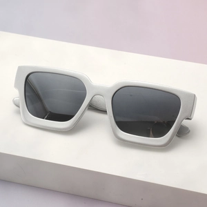 Close-up of matte silver square frame sunglasses on a minimalist white platform