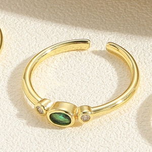 Macro shot of gold adjustable ring featuring oval green gemstone and clear side stones