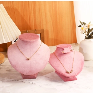 Pink velvet jewelry display busts on marble tabletop with elegant minimalist backdrop