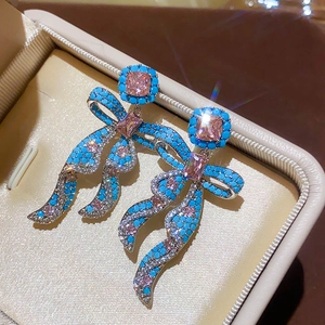Macro shot of vintage bow earrings with pink square crystals and blue bead accents