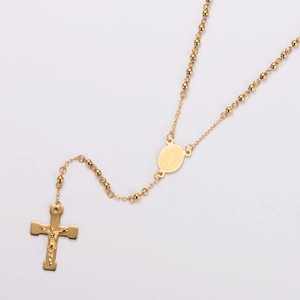 Detail of golden rosary necklace featuring Guadalupe medal and polished cross pendant
