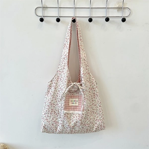 Detail of floral tote bag with gingham pocket and colorful embroidered brand label