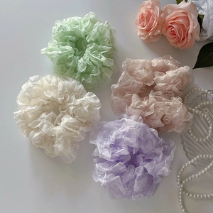Close-up of four lace organza scrunchies in pastel green, white, pink, and lilac colors