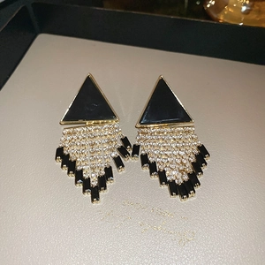 Detail of tassel earrings with black triangles, gold metal, and sparkling rhinestones