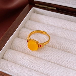 Détail d'une bague ouverte avec pierre ovale jaune sur un présentoir en tissu blanc