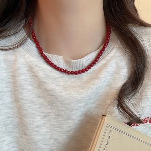 Close-up of minimalist red glass bead necklace on model with elegant metal clasp