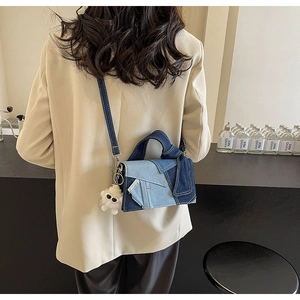 Détail du sac patchwork en denim déconstruit avec charm ours en peluche sur un modèle