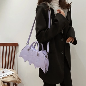 Detail of a purple bat-shaped gothic shoulder bag featuring intricate spider web embroidery