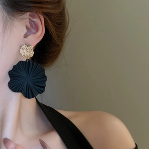 Detailaufnahme mattschwarzer Blumen-Ohrhänger mit goldenen Scheiben am Modell