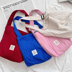 Detailed view of quilted pleated tote bags in red, blue, pink, and beige fabric colors