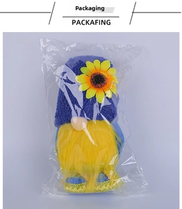Detail of sunflower gnome plush in clear packaging with yellow beard and knit hat