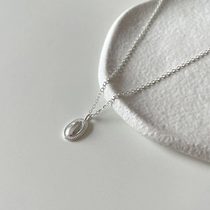 Minimalist 925 sterling silver oval pendant necklace with polished finish on ceramic tray