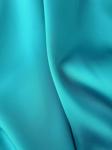 Detail of turquoise satin fabric showing luxurious pleated texture and soft glossy sheen