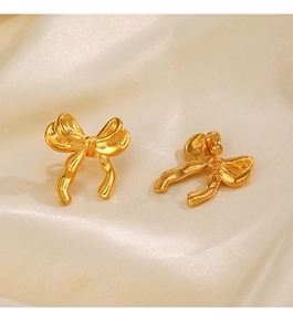 Gros plan de boucles d'oreilles nœud plaquées or 18K sur un tissu en soie élégant